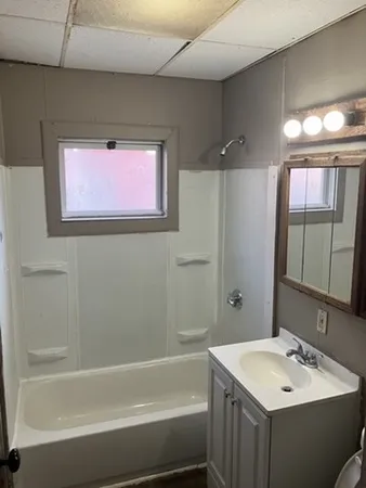 a bathroom with a bathtub sink vanity and mirror