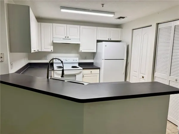 a kitchen with kitchen island a sink a stove a refrigerator and cabinets