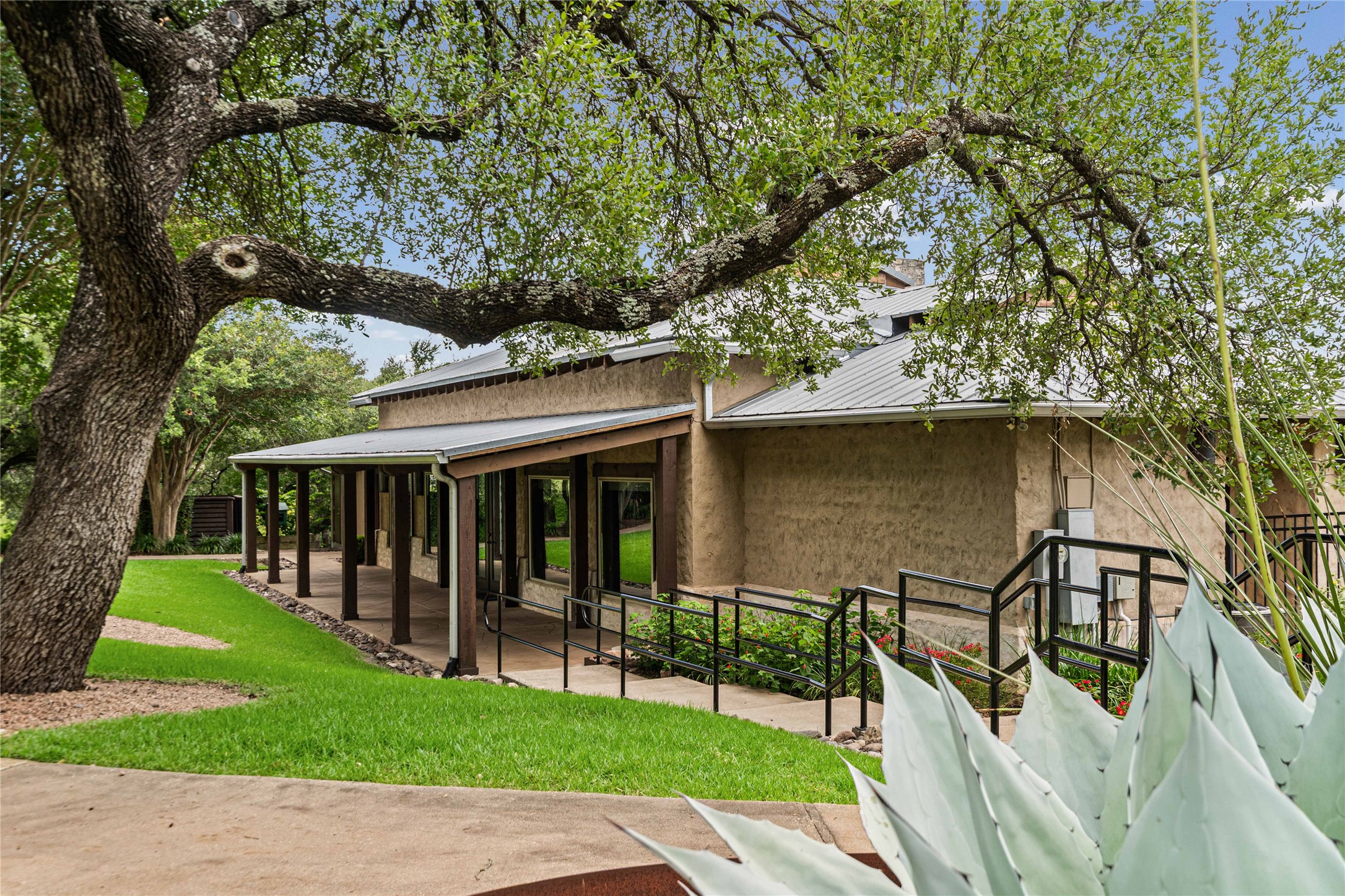 10700 Pointe View Drive Austin, TX 78738 - Photo 29 of 35 Mature trees and lush landscaping adorn this inviting stucco residence, offering a welcoming entry.