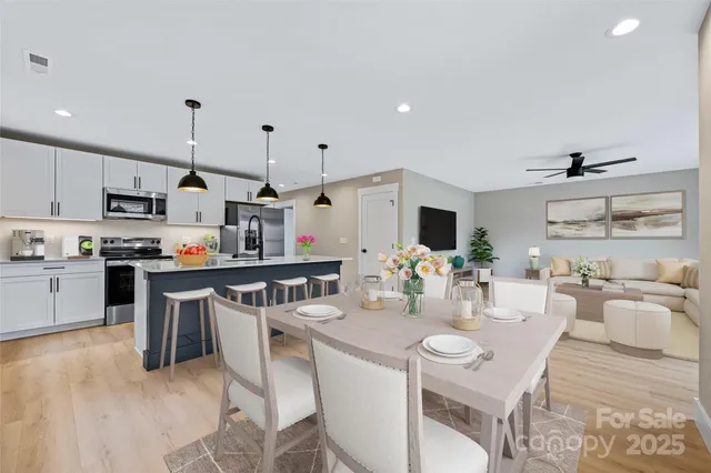 a kitchen with stainless steel appliances kitchen island granite countertop a sink dishwasher stove and white cabinets with wooden floor