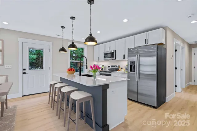 a kitchen with kitchen island white cabinets and stainless steel appliances