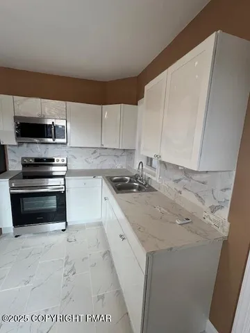 a kitchen with stainless steel appliances granite countertop a stove a sink and a microwave