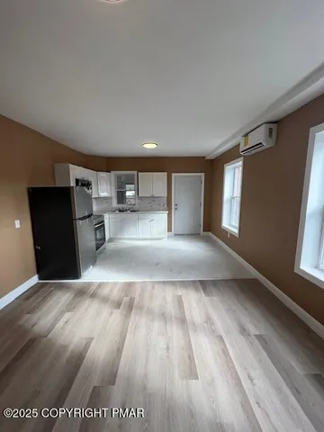 a view of empty room with wooden floor and window