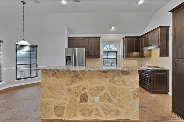 a kitchen with stainless steel appliances granite countertop a stove a sink and a refrigerator