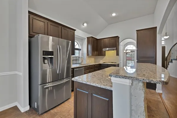 a kitchen with stainless steel appliances granite countertop a refrigerator a stove and a sink