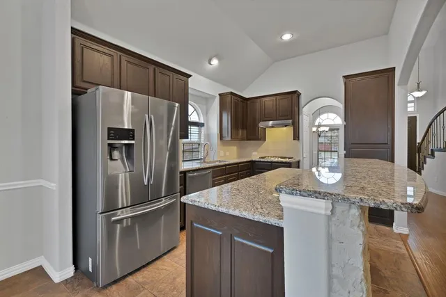 a kitchen with stainless steel appliances granite countertop a refrigerator a stove and a sink