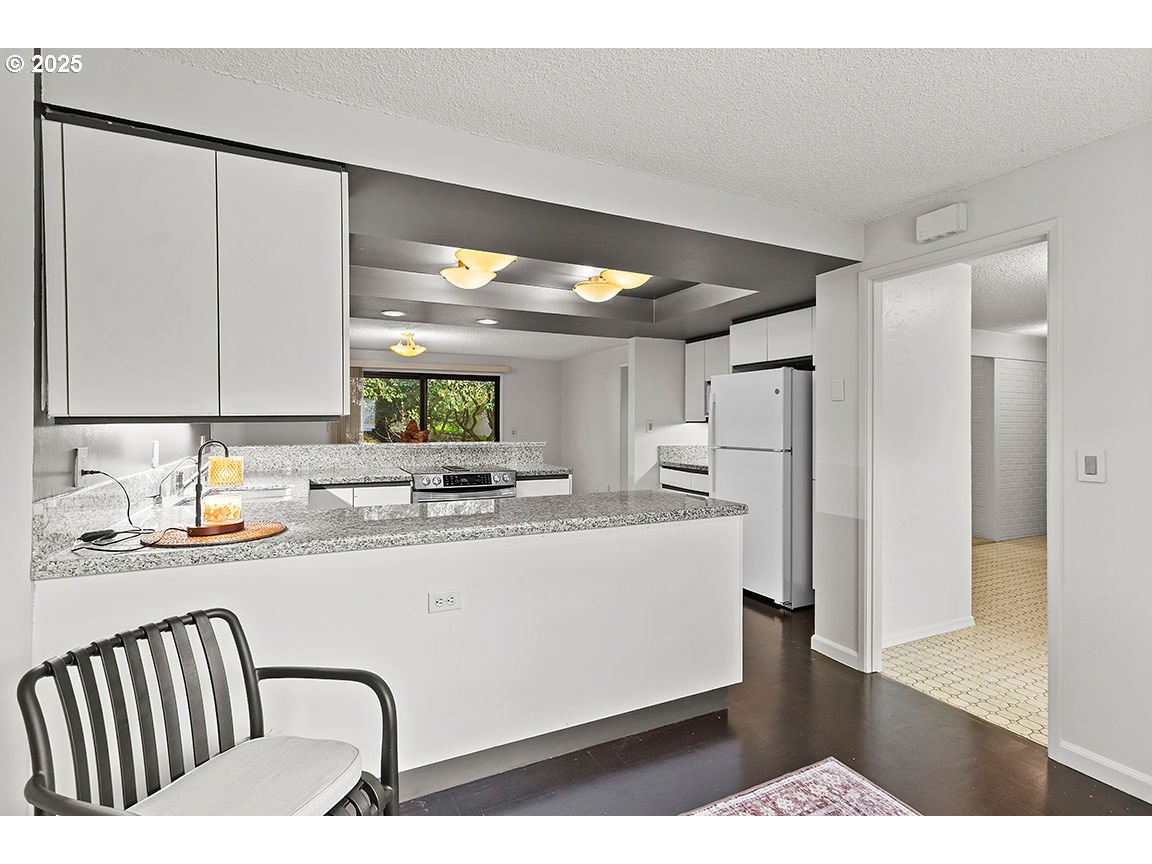 9 Britten Court Lake Oswego, OR 97035 - Photo 13 of 48 a kitchen with stainless steel appliances kitchen island granite countertop a refrigerator a sink a stove and white cabinets with wooden floor