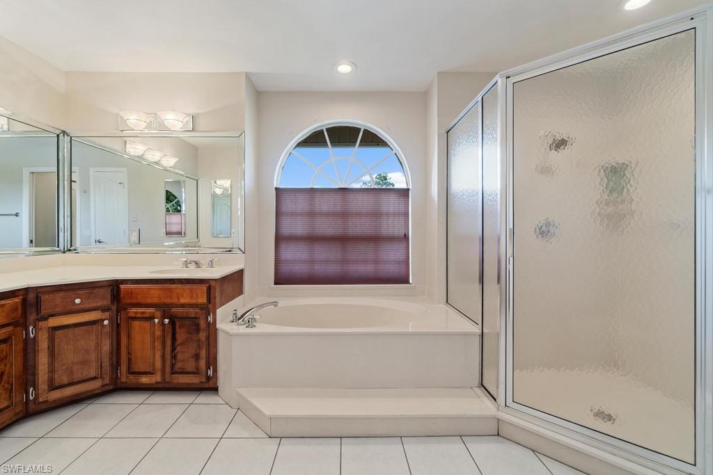 560 Henley Drive Naples, FL 34104 - Photo 11 of 16 a bathroom with a tub a sink and a mirror