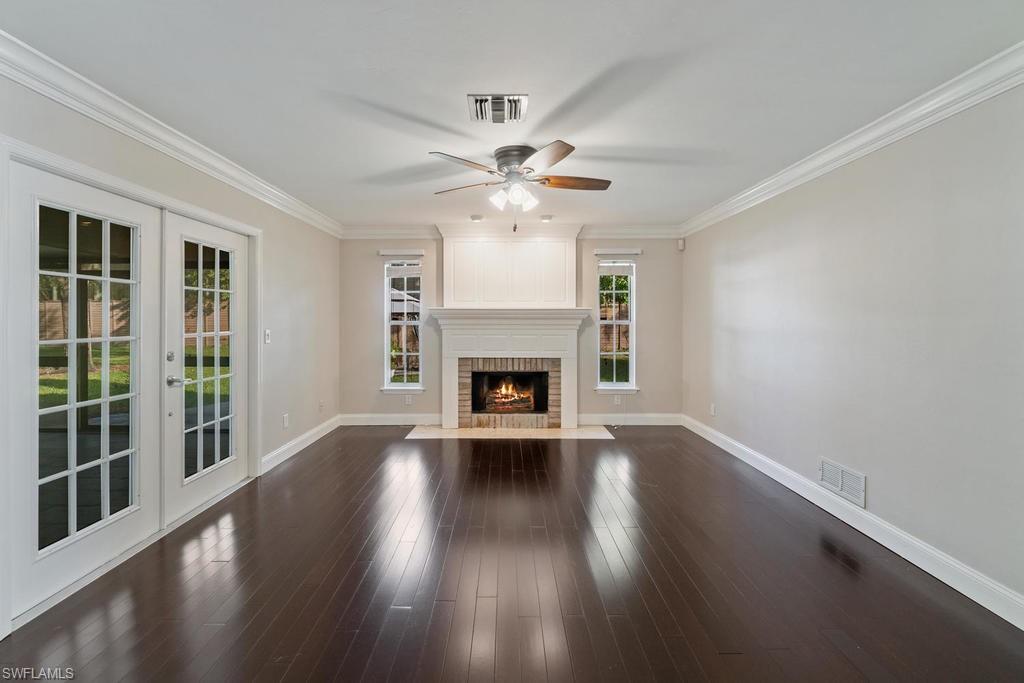 560 Henley Drive Naples, FL 34104 - Photo 4 of 16 a view of an empty room with wooden floor fireplace and a window