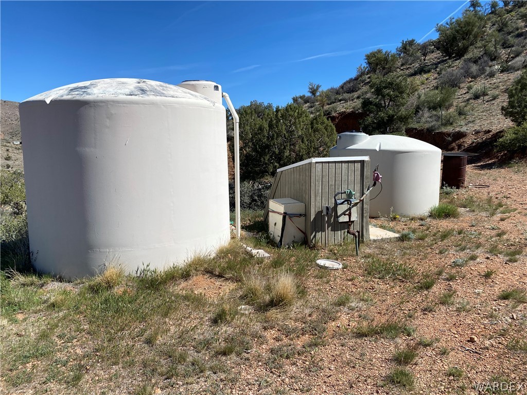 9095 Elliott Ridge Road Kingman, AZ 86401 - Photo 40 of 54 The property includes two large tanks and a utility structure, set against a natural, sloped landscape with sparse vegetation