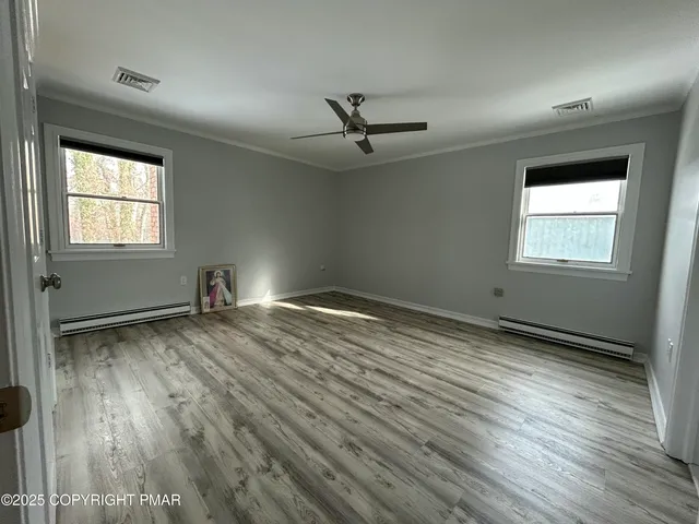 an empty room with wooden floor and windows