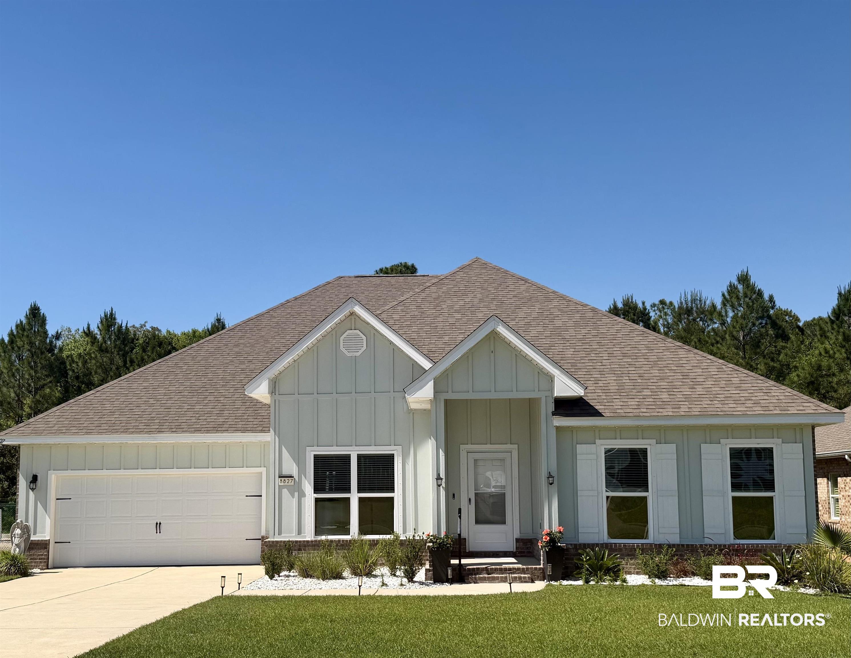 8827 Calverton Street Foley, AL 36535 - Photo 1 of 57 Single-story residence featuring light-colored vertical and horizontal siding, a two-car garage with a concrete driveway, and a gabled entry