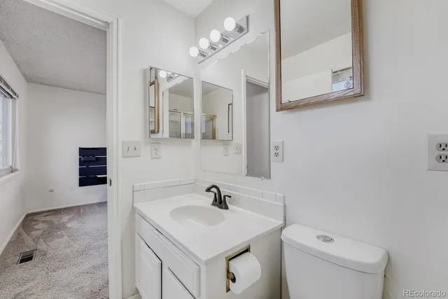 a bathroom with a sink vanity granite toilet and a mirror