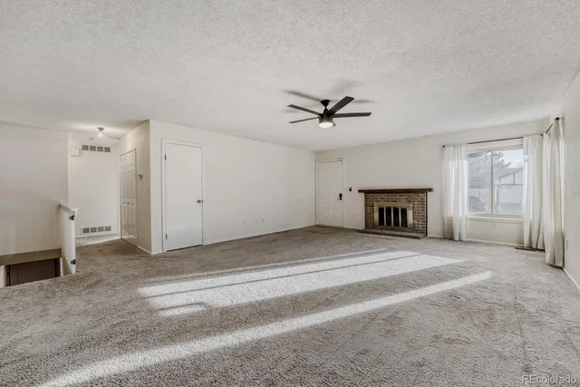 a view of livingroom with a fireplace a ceiling fan and a window