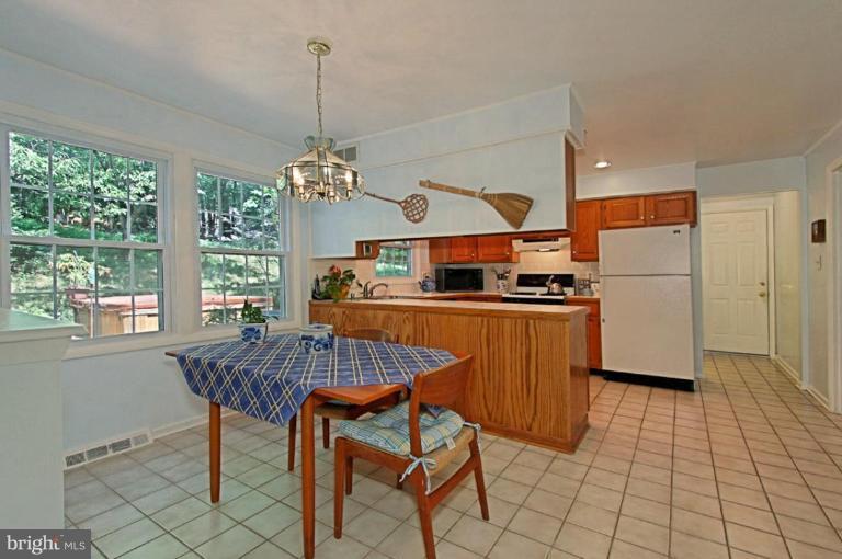 11412 Running Cedar Road Reston, VA 20191 - Photo 14 of 18 a kitchen with stainless steel appliances granite countertop a stove a refrigerator a kitchen island a dining table and chairs with the chandelier