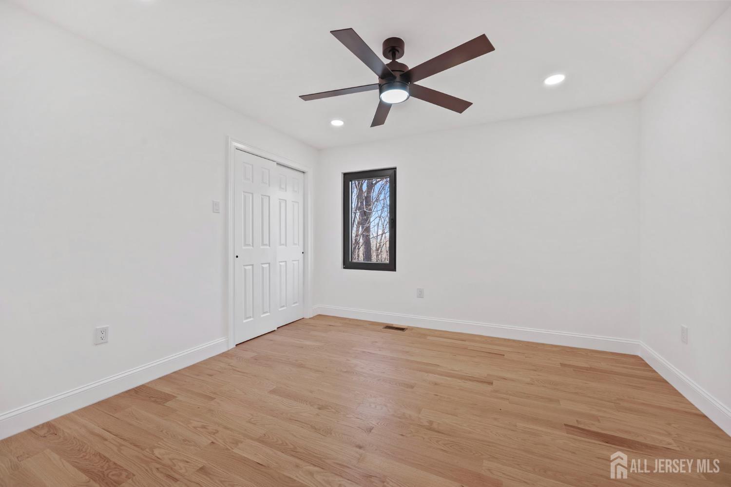 120 Nolan Road Morganville, NJ 07751 - Photo 33 of 85 an empty room with wooden floor ceiling fan and windows