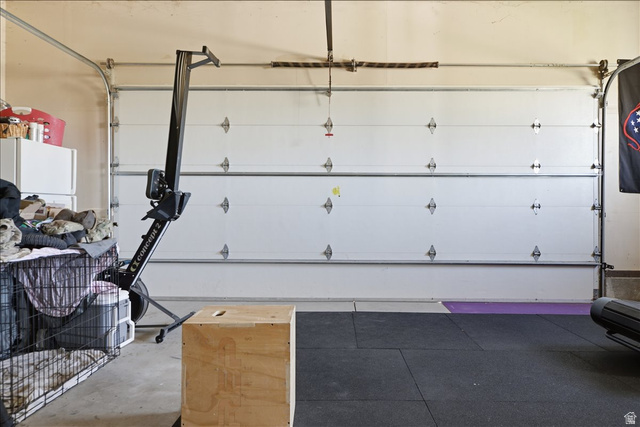 1634 West Arimo Road Arimo, ID 83214 - Photo 23 of 89 Garage interior featuring concrete flooring, a white sectional garage door, exposed garage door tracks, and a black rubber mat floor section