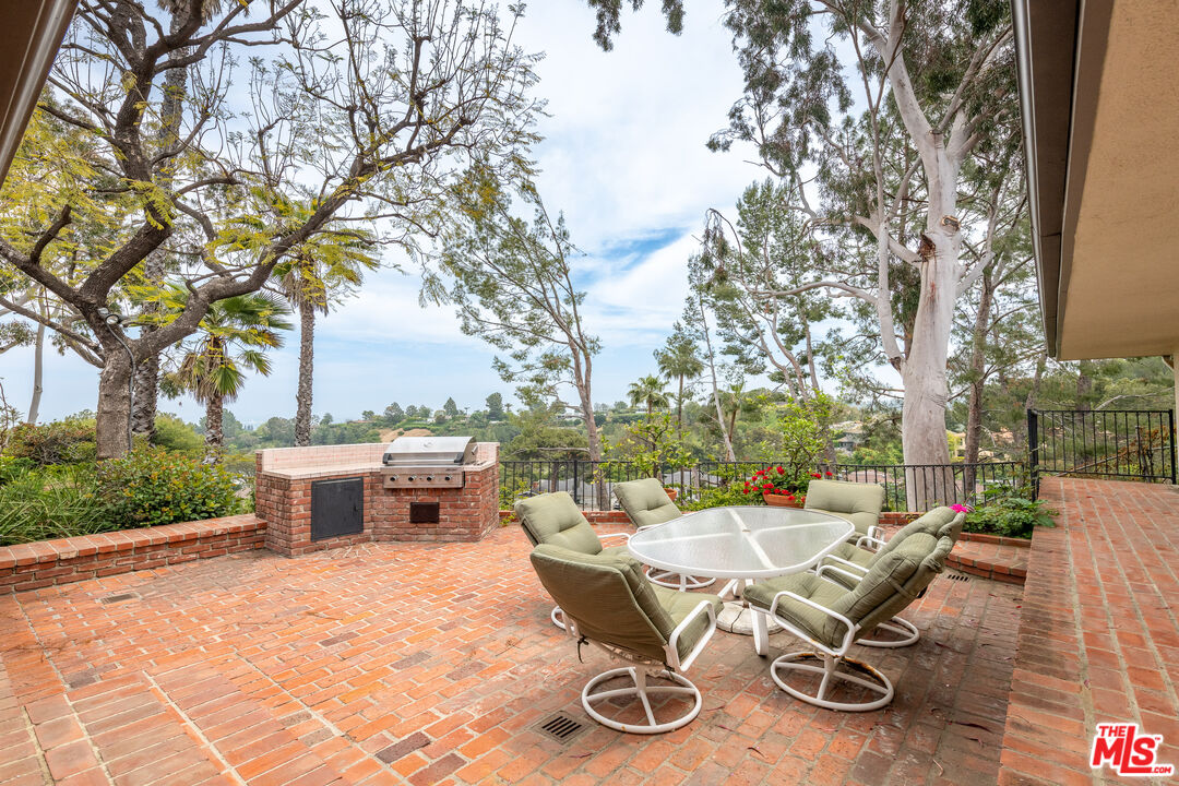 16331 Tudor Drive Encino, CA 91436 - Photo 46 of 71 a view of a backyard with table and chairs with a fire pit and a large tree