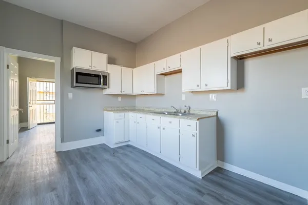 a kitchen with wooden floors and white cabinets
