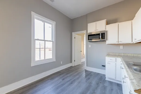 a view of kitchen with stainless steel appliances granite countertop white cabinets and window