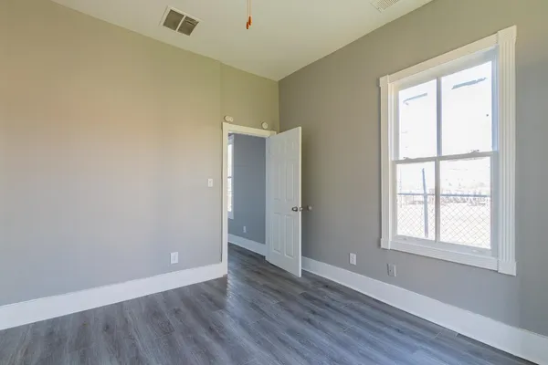 an empty room with wooden floor and windows