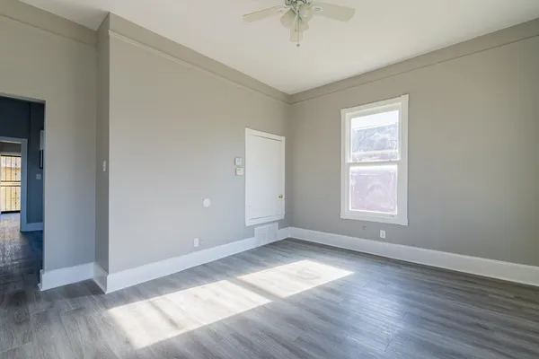 an empty room with wooden floor and windows