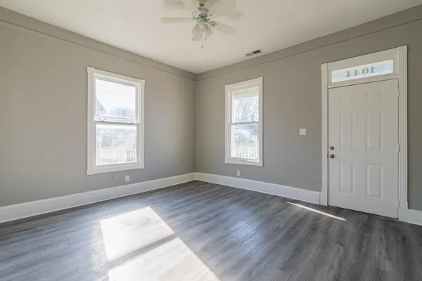 a view of an empty room with wooden floor and a window