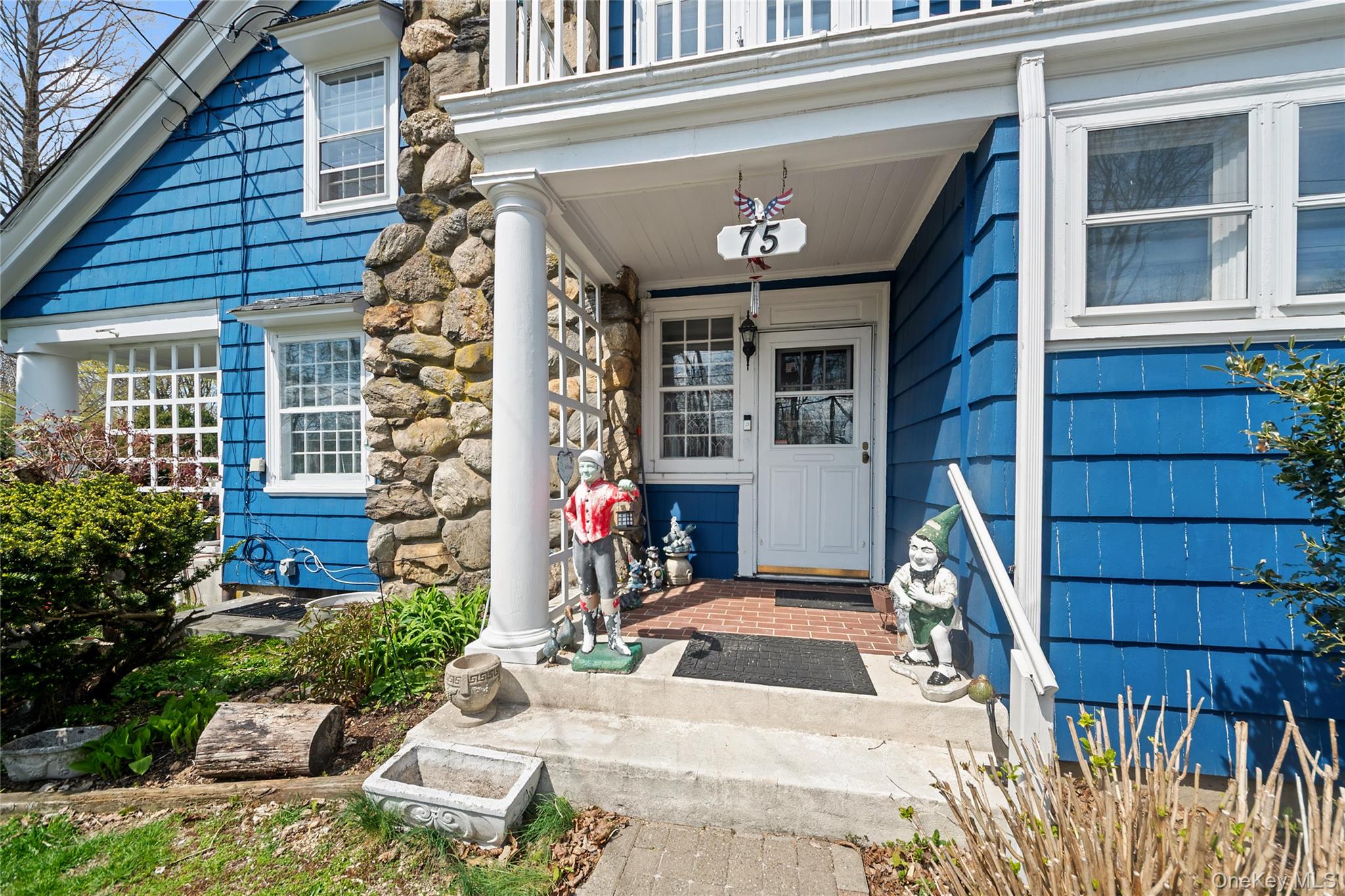 Welcoming front porch featuring a white entry door with glass panels, supported by a classic white column, and a prominent stone facade