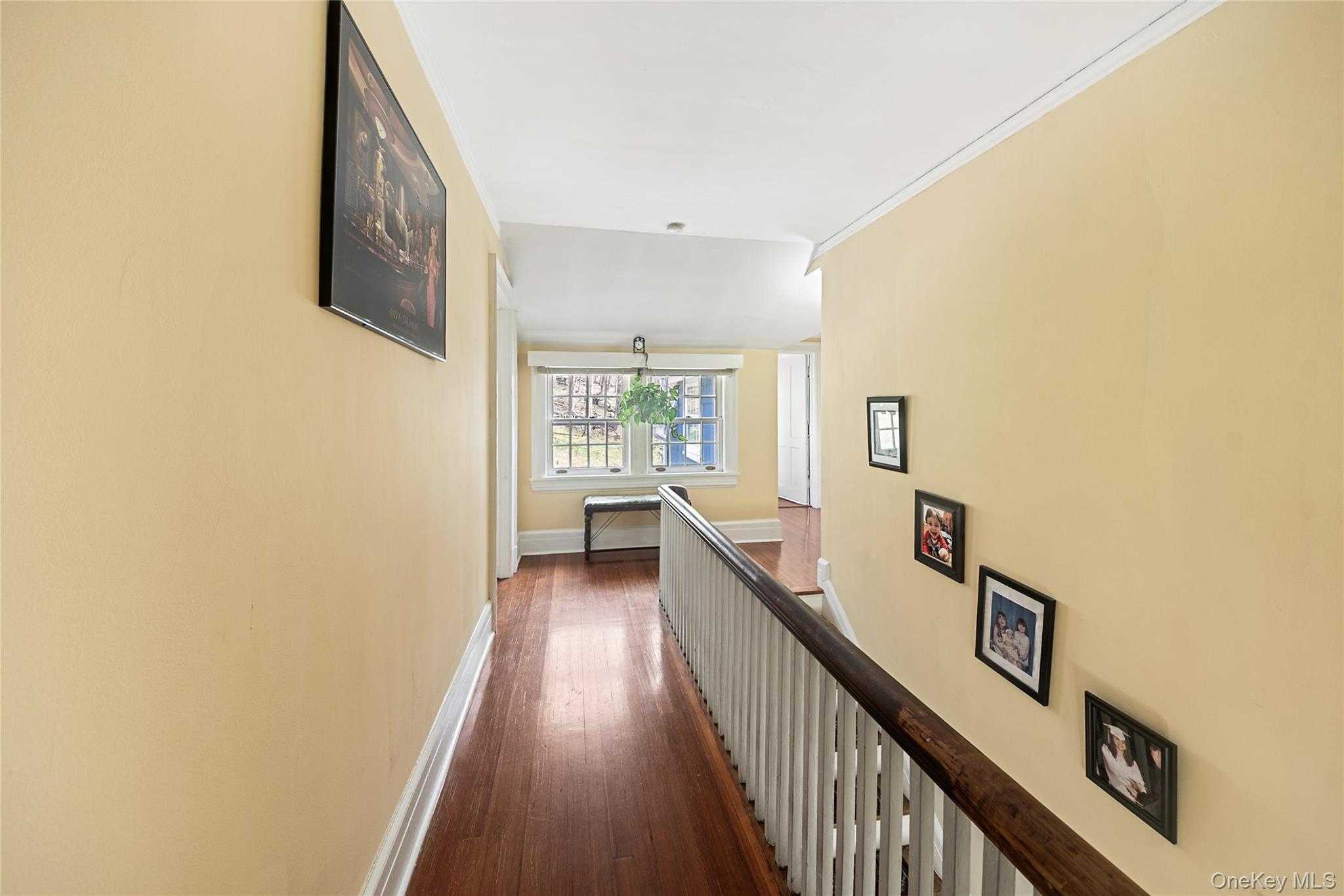 75 Chappaqua Road Briarcliff Manor, NY 10510 - Photo 15 of 50 Hallway featuring wood-finish flooring, white crown molding, a white spindle railing, and a window with multiple panes