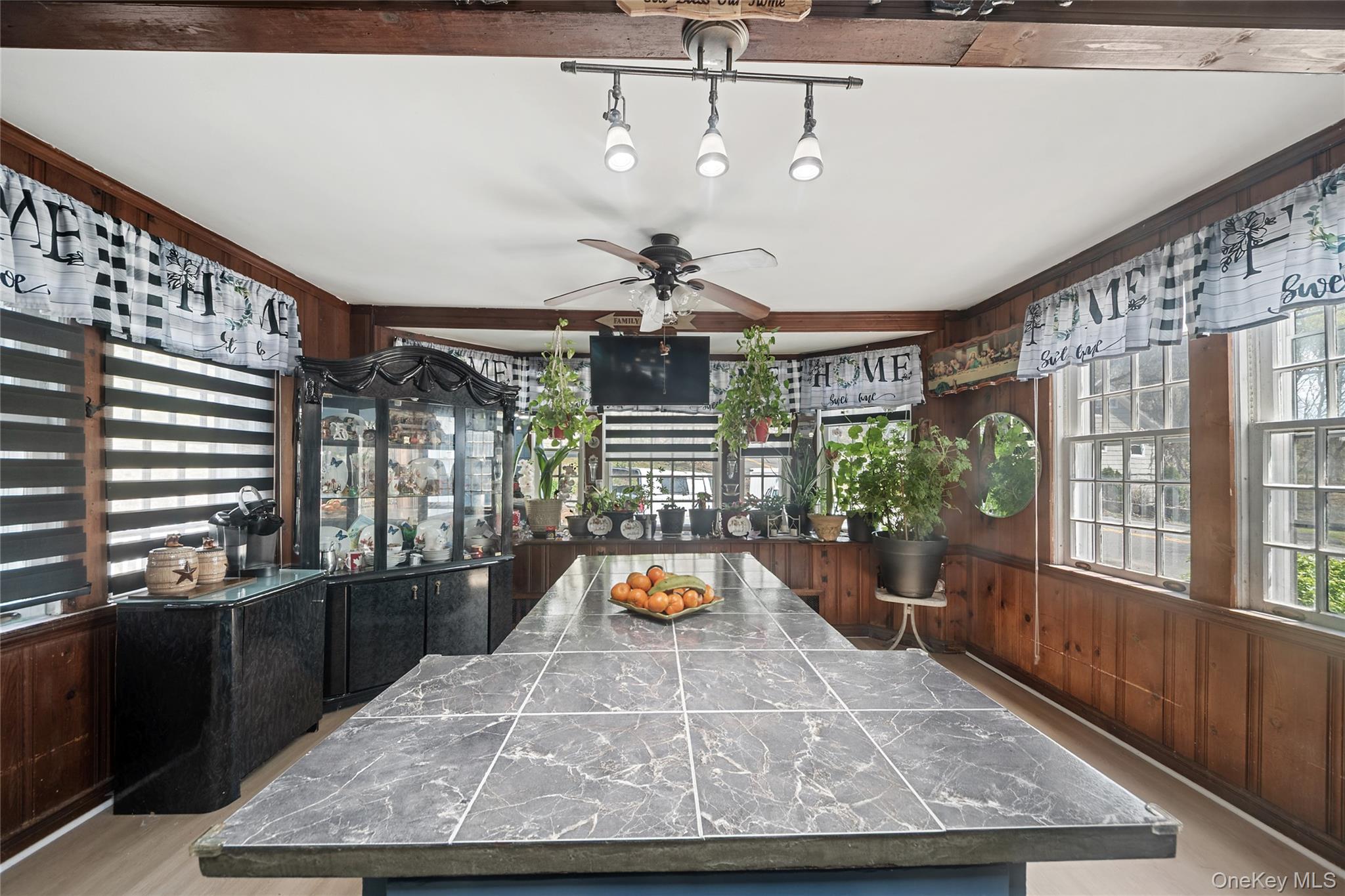 75 Chappaqua Road Briarcliff Manor, NY 10510 - Photo 6 of 50 Spacious kitchen featuring a large central island with a tiled countertop, natural wood paneling, multiple windows, exposed ceiling beams, and recessed lighting