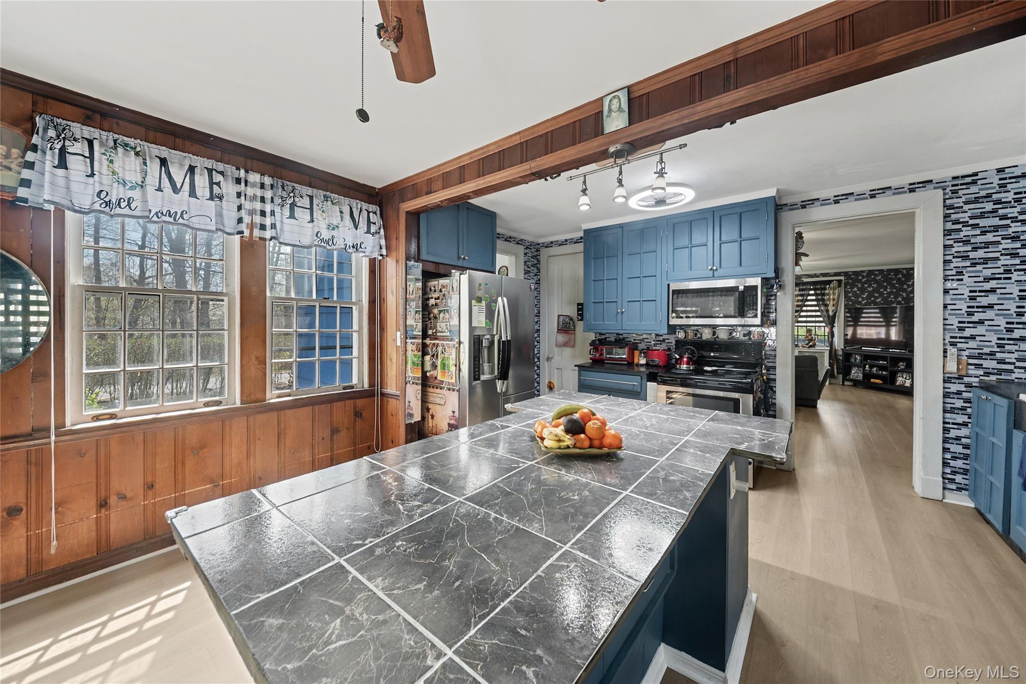 75 Chappaqua Road Briarcliff Manor, NY 10510 - Photo 8 of 50 Kitchen featuring a large island with tiled countertop, blue cabinetry, stainless steel appliances, and light wood-finish flooring