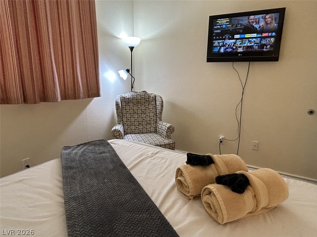 210 East Flamingo Road, Unit 137 Las Vegas, NV 89169 - Photo 15 of 32 A well-appointed bedroom offering comfortable accommodations with a wall-mounted television and corner reading chair.