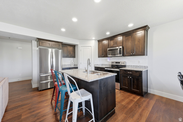 28 East Ginger Gold Road Santaquin, UT 84655 - Photo 13 of 36 Kitchen featuring a center island, stainless steel appliances, dark wood cabinetry, and granite countertops