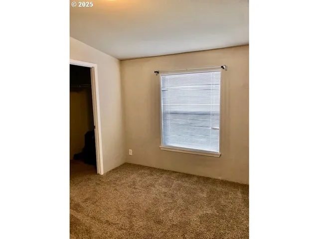 a view of an empty room with closet and a window