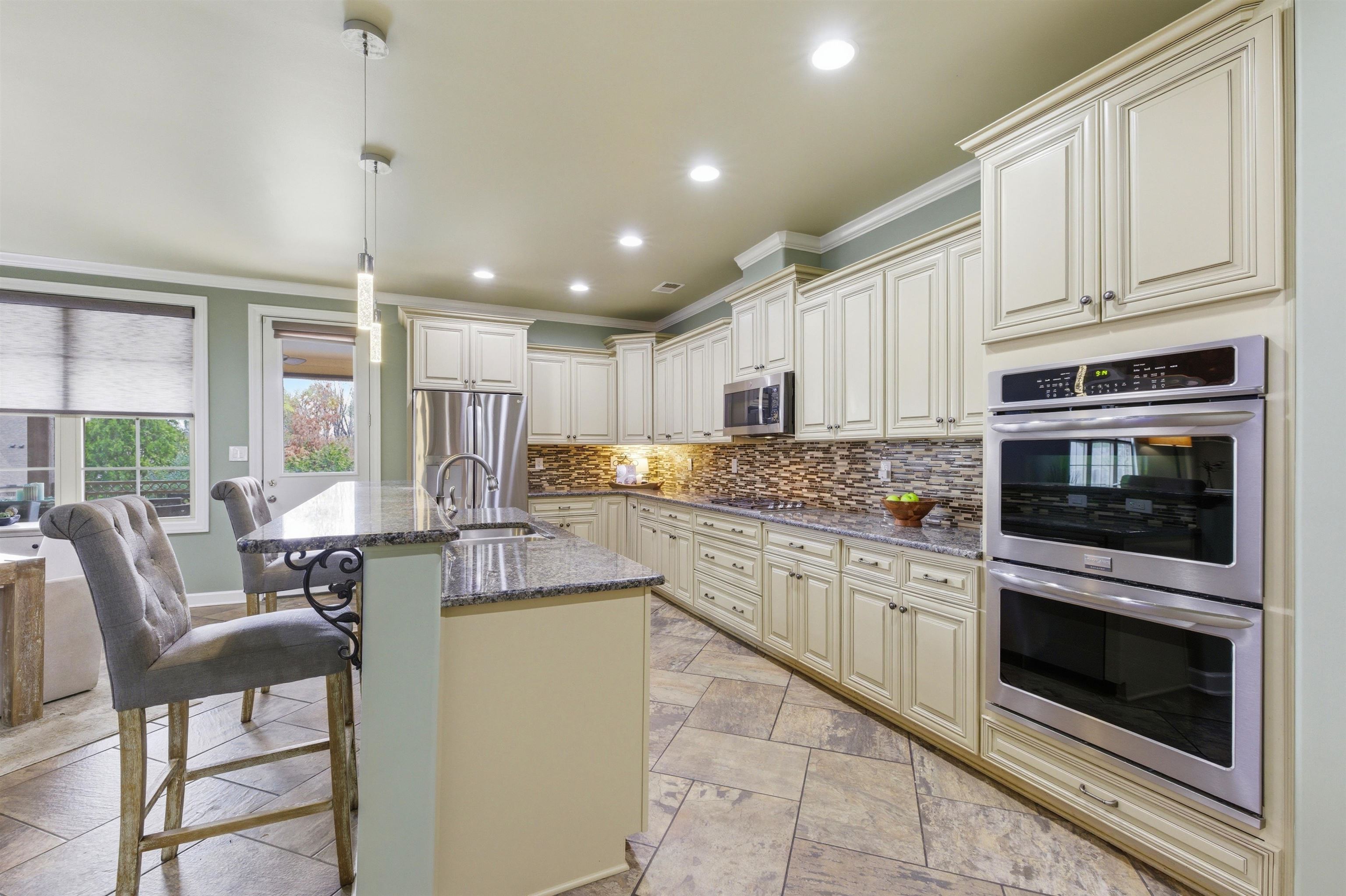 5956 Windsor Falls Loop Arlington, TN 38002 - Photo 14 of 40 a kitchen with stainless steel appliances granite countertop a stove top oven a sink dishwasher a dining table and chairs with wooden floor