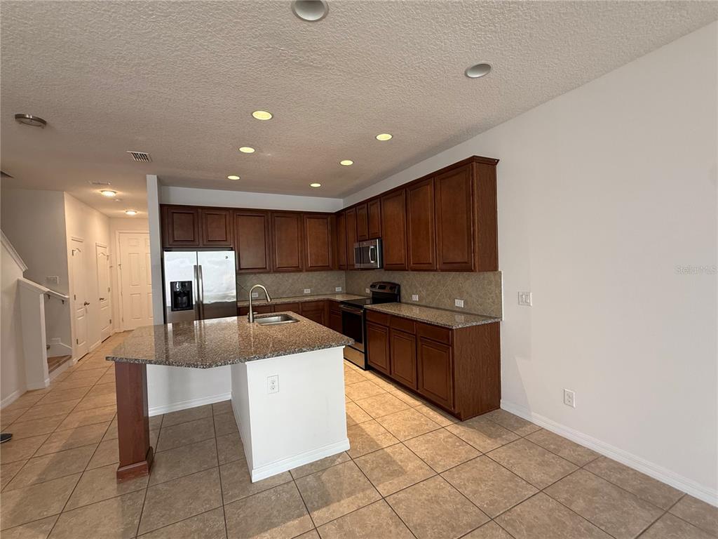 7605 Ripplepointe Way Windermere, FL 34786 - Photo 5 of 27 a large kitchen with stainless steel appliances granite countertop a large counter top and a stove