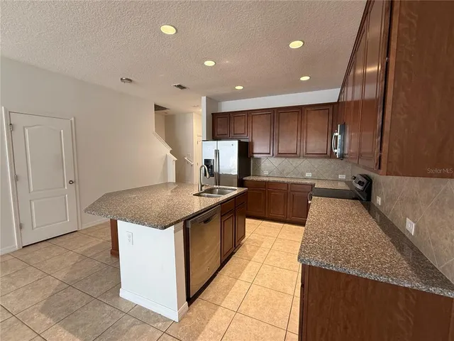 a large kitchen with granite countertop a stove a sink and a microwave oven