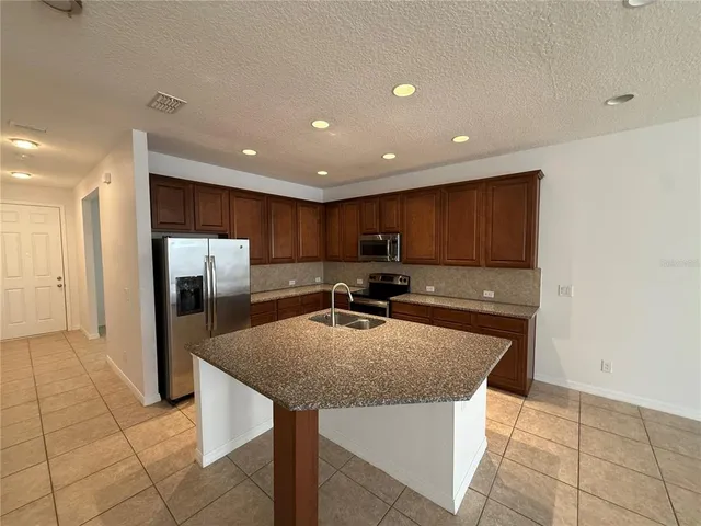 a kitchen with stainless steel appliances granite countertop a sink and a refrigerator