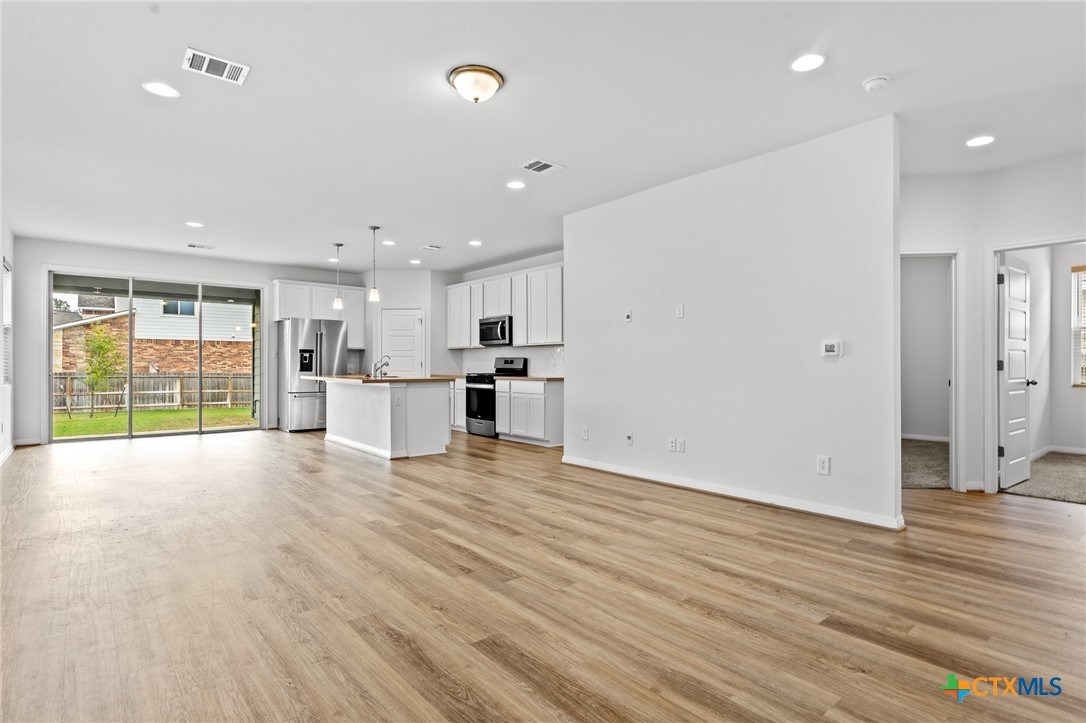 448 Chaste Tree Drive San Marcos, TX 78666 - Photo 11 of 31 a view of an empty room with wooden floor and a kitchen