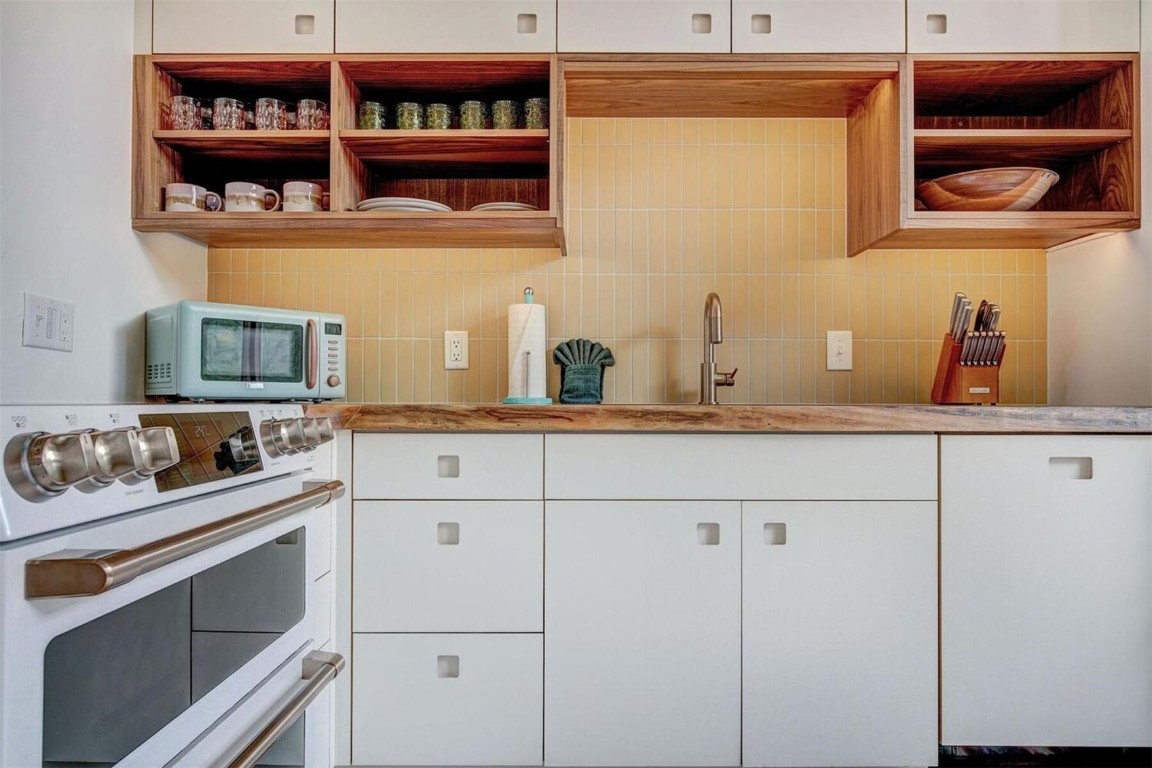 Kitchen with white cabinets, white appliances, sink, and decorative backsplash