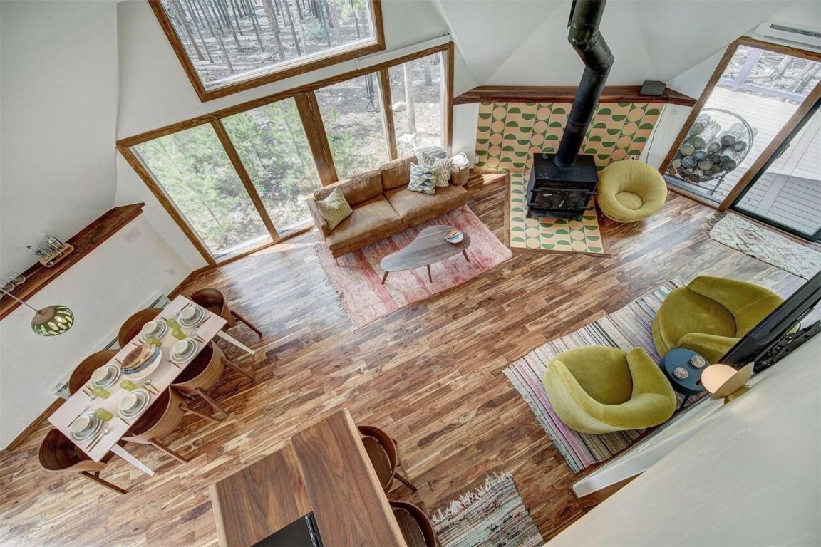 Open Living room with hardwood floors, a wood stove, and a high ceiling