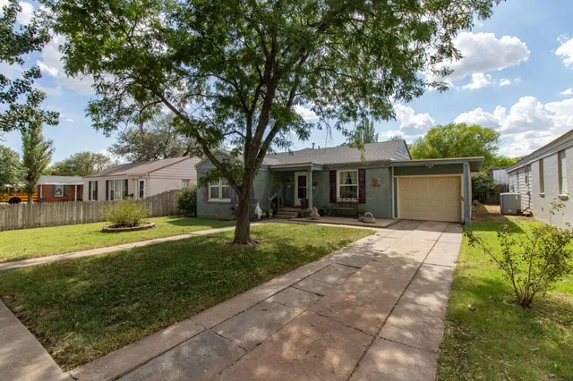 a front view of a house with a yard and trees