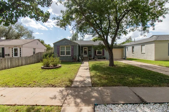 a front view of a house with a yard and trees