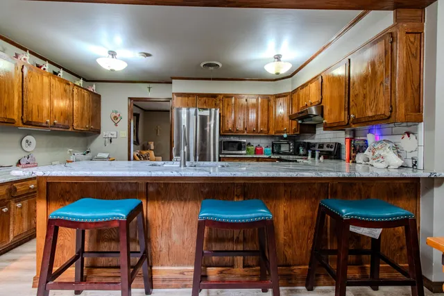 a kitchen with stainless steel appliances granite countertop table chairs sink and cabinets