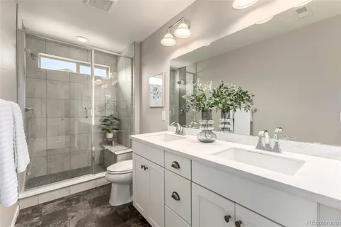 a bathroom with a double vanity sink toilet and shower