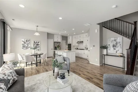 a living room with furniture and kitchen view with wooden floor