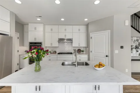 a kitchen with kitchen island granite countertop sink and white cabinets