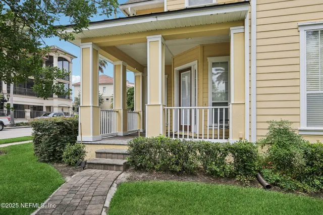 a view of a brick house with a yard potted plants and a bench