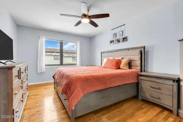 a spacious bedroom with a bed and a flat tv screen on dresser