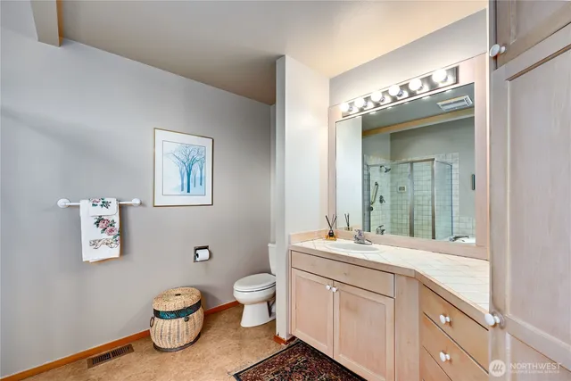 a bathroom with a granite countertop toilet sink and mirror